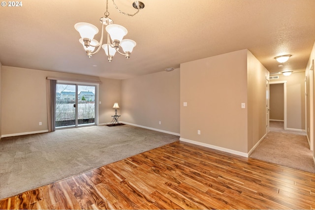 spare room with hardwood / wood-style floors, a textured ceiling, and an inviting chandelier