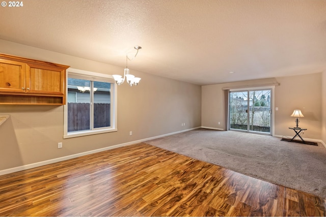 spare room with a notable chandelier, carpet floors, and a textured ceiling