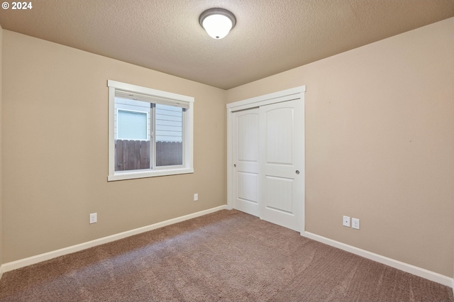 unfurnished bedroom featuring carpet flooring, a textured ceiling, and a closet