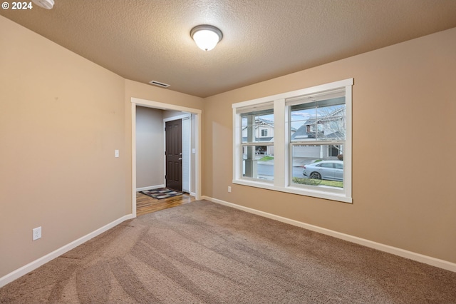 carpeted empty room featuring a textured ceiling