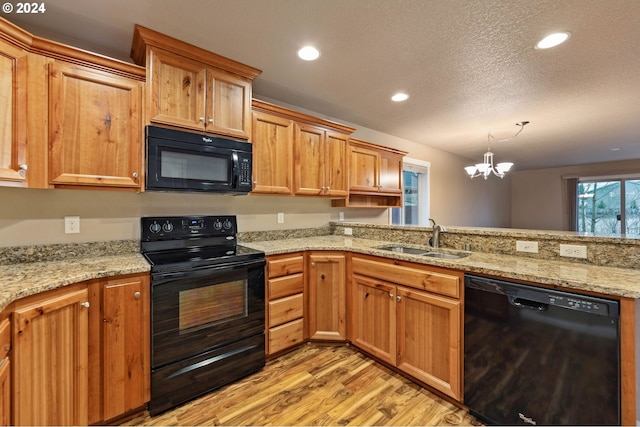 kitchen with sink, light stone counters, light hardwood / wood-style flooring, a chandelier, and black appliances