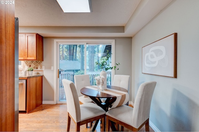 dining area with a textured ceiling and light hardwood / wood-style flooring