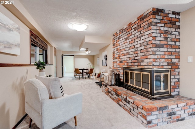 carpeted living room featuring a brick fireplace and a textured ceiling