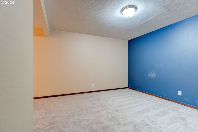 spare room featuring a textured ceiling and light carpet