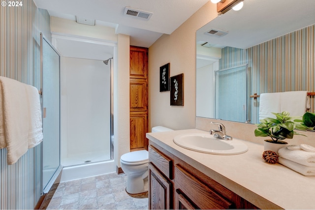 bathroom featuring a shower with door, vanity, and toilet