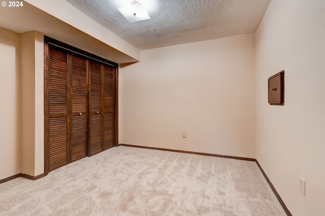 unfurnished bedroom featuring light colored carpet, a textured ceiling, and a closet