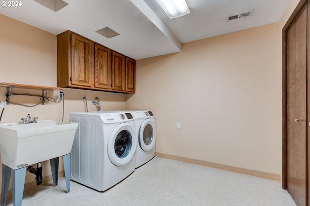 clothes washing area featuring cabinets, light colored carpet, and washer and clothes dryer