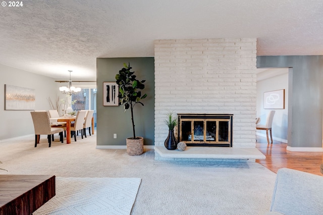 carpeted living room with a fireplace, a chandelier, and a textured ceiling