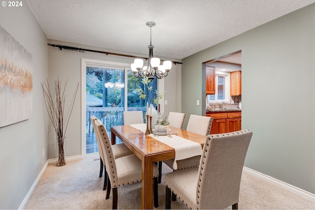 carpeted dining area with plenty of natural light, a textured ceiling, and a notable chandelier