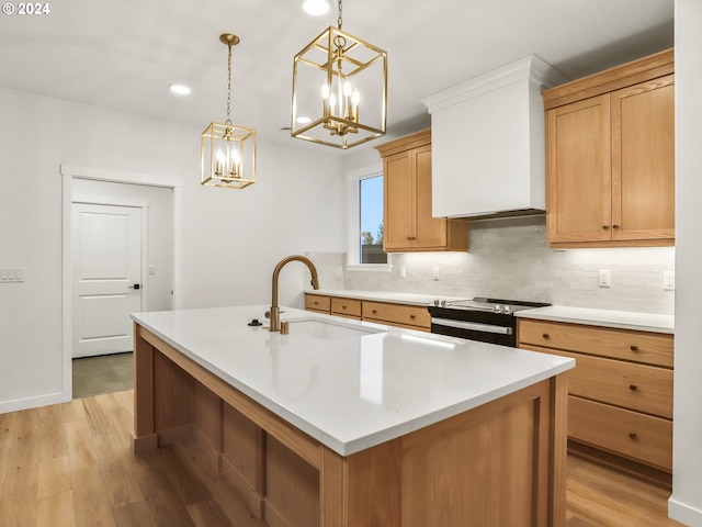 kitchen with light wood-type flooring, electric range oven, a kitchen island with sink, and sink