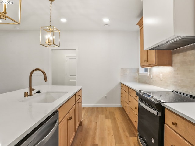 kitchen featuring sink, stainless steel appliances, light hardwood / wood-style flooring, a notable chandelier, and decorative light fixtures