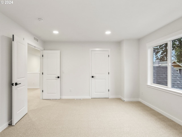 unfurnished bedroom featuring light carpet and multiple windows