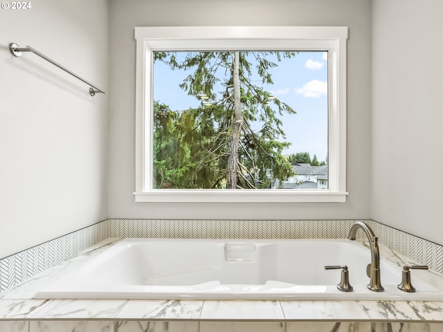 bathroom with a healthy amount of sunlight and tiled bath