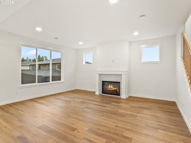 unfurnished living room with a tile fireplace and light hardwood / wood-style floors