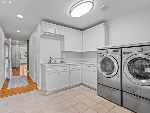 washroom featuring cabinets, light wood-type flooring, sink, and washer and dryer