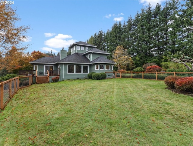 rear view of property with a wooden deck and a lawn