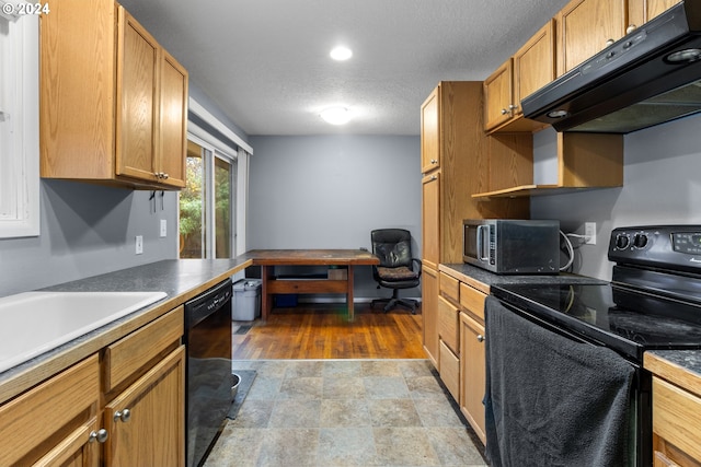 kitchen featuring built in desk, black appliances, a textured ceiling, and ventilation hood