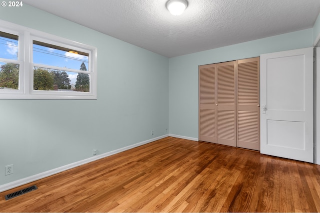 unfurnished bedroom featuring a closet, hardwood / wood-style floors, and a textured ceiling