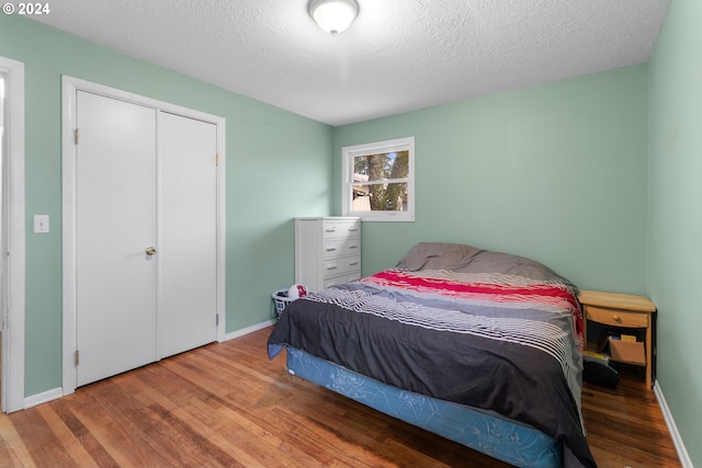 bedroom with hardwood / wood-style floors, a textured ceiling, and a closet