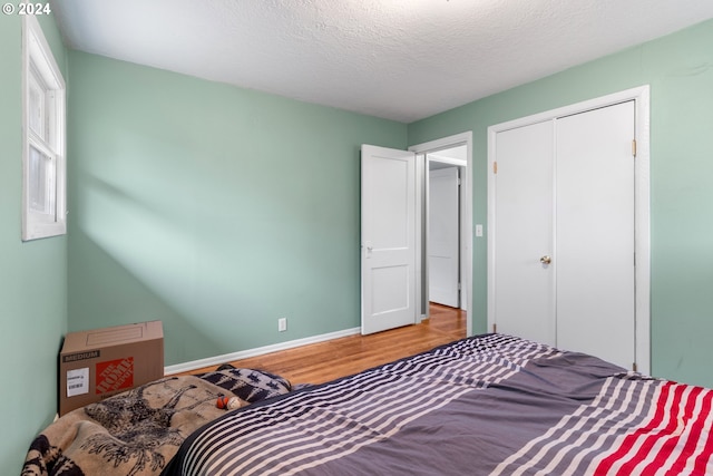 bedroom with hardwood / wood-style floors, a textured ceiling, and a closet