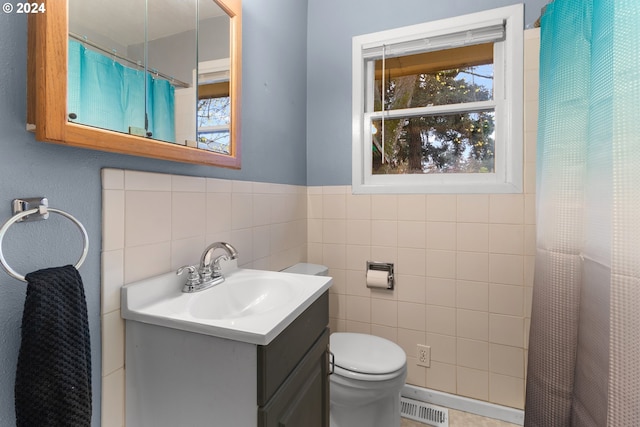 bathroom featuring vanity, toilet, and tile walls