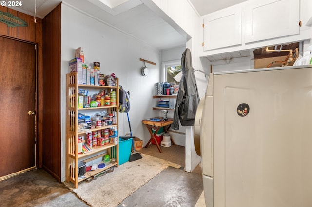 interior space featuring white cabinets, washer / clothes dryer, and wood walls