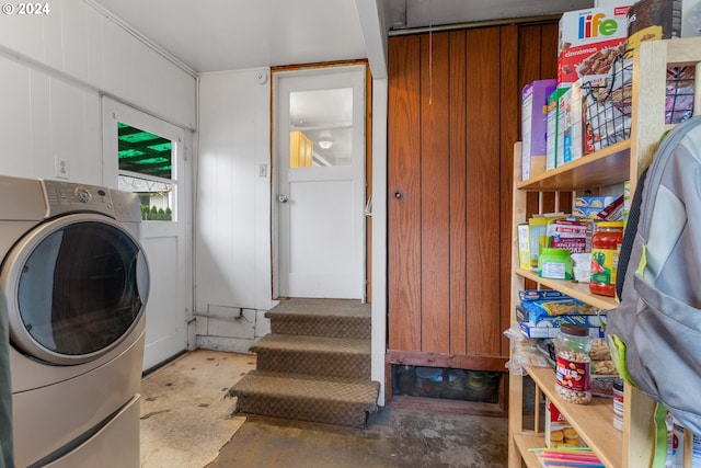 clothes washing area with wood walls and washer / dryer