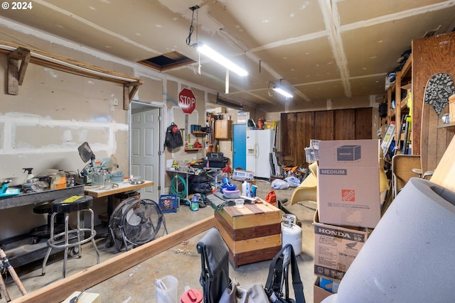 garage with white refrigerator with ice dispenser and a workshop area