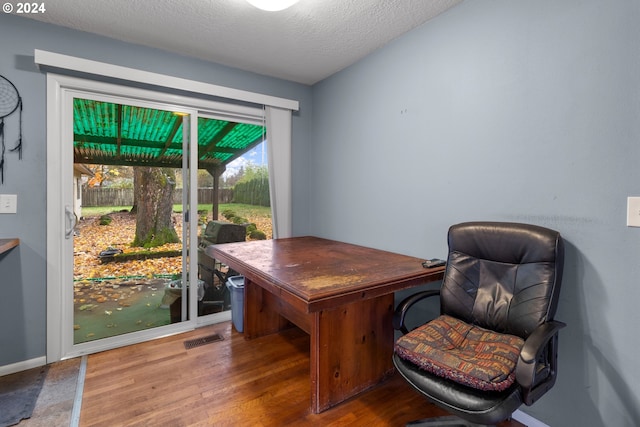 office area with wood-type flooring and a textured ceiling