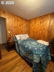 bedroom with wooden walls and hardwood / wood-style flooring