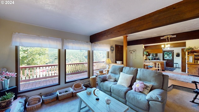 carpeted living room with beam ceiling, a textured ceiling, and a chandelier