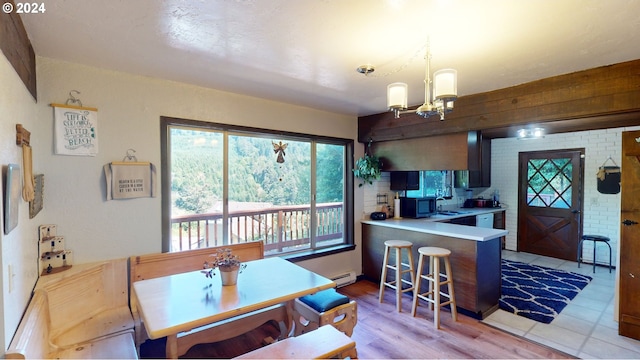 interior space featuring sink, light wood-type flooring, kitchen peninsula, a notable chandelier, and baseboard heating