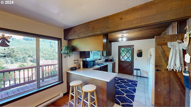 kitchen featuring brick wall, a breakfast bar, hardwood / wood-style flooring, kitchen peninsula, and a baseboard heating unit