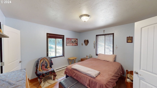 bedroom with hardwood / wood-style floors and a baseboard heating unit