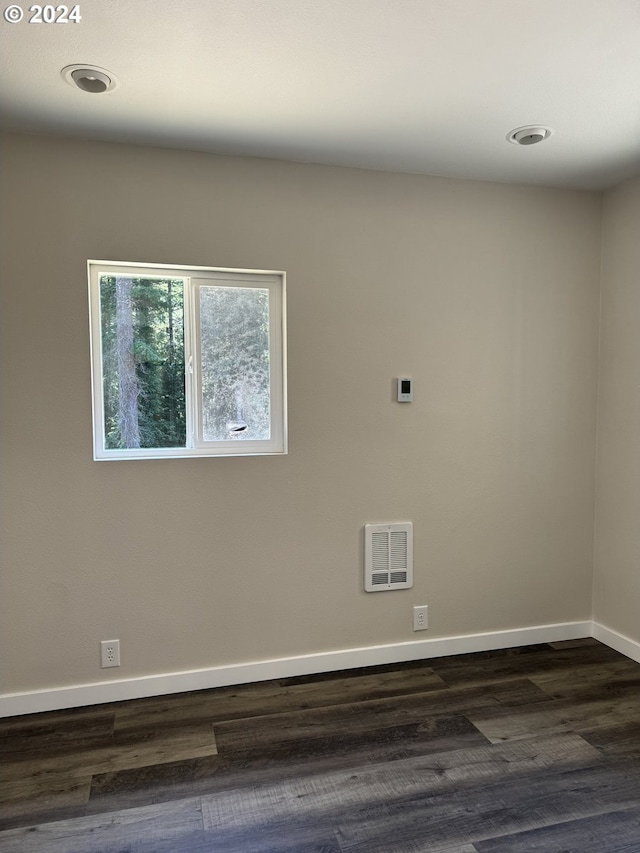 empty room with heating unit and dark hardwood / wood-style flooring