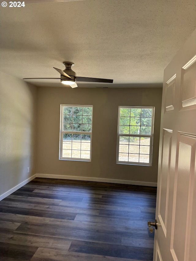 empty room with dark hardwood / wood-style floors, ceiling fan, and a wealth of natural light