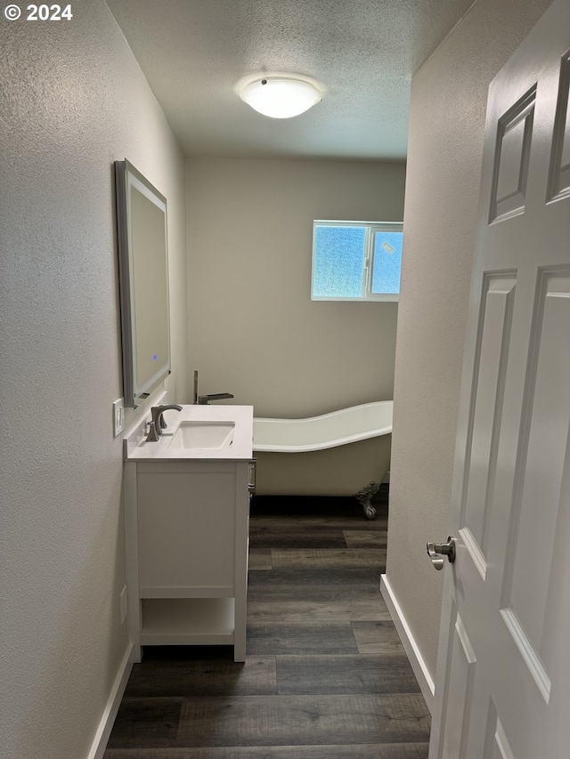 bathroom featuring wood-type flooring, a textured ceiling, a bath, and vanity