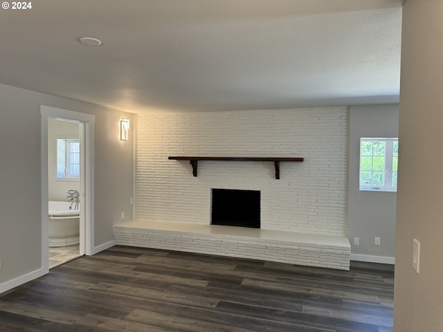 unfurnished living room with a textured ceiling, a fireplace, and dark wood-type flooring