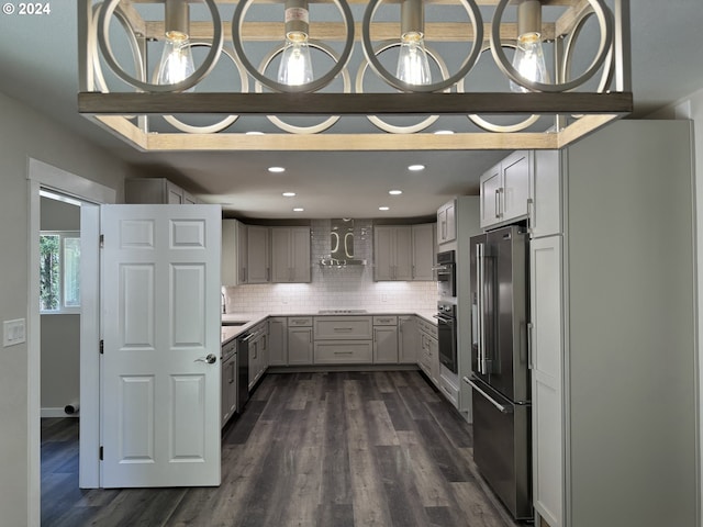 kitchen featuring appliances with stainless steel finishes, backsplash, wall chimney exhaust hood, dark hardwood / wood-style flooring, and gray cabinets