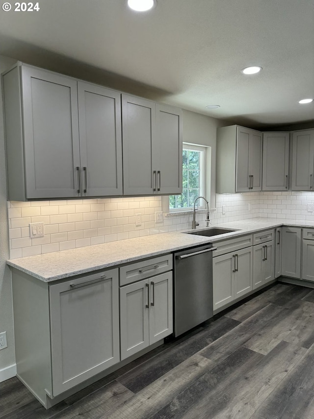 kitchen featuring tasteful backsplash, gray cabinets, stainless steel dishwasher, dark hardwood / wood-style floors, and sink