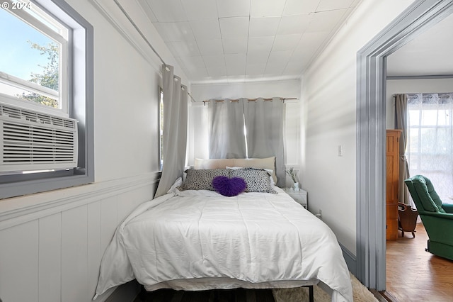 bedroom with ornamental molding, wood-type flooring, and cooling unit