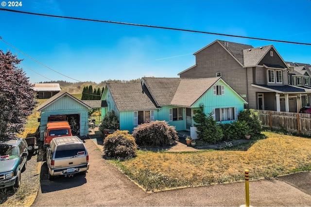 view of front of property with an outdoor structure, a front yard, fence, and a detached garage