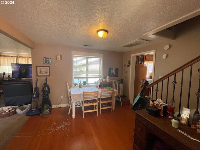 dining area with wood-type flooring and a textured ceiling