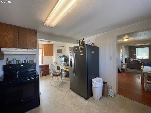 kitchen with ornamental molding, black / electric stove, a textured ceiling, and stainless steel fridge