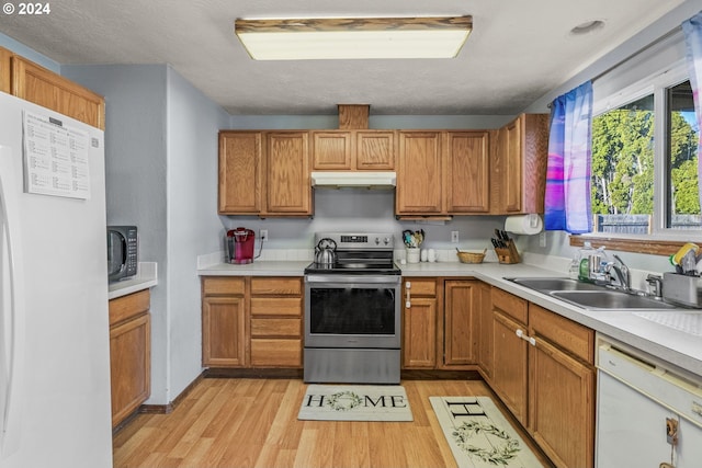 kitchen featuring a textured ceiling, sink, white appliances, and light hardwood / wood-style flooring