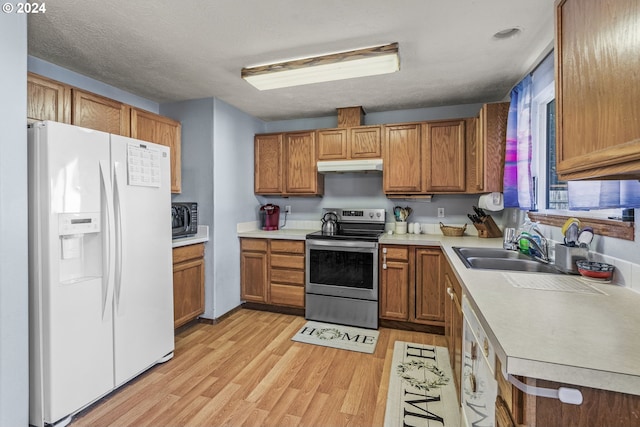 kitchen with a textured ceiling, stainless steel appliances, light hardwood / wood-style floors, and sink