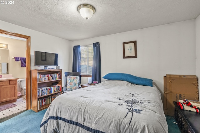 bedroom with light colored carpet, a textured ceiling, and ensuite bath