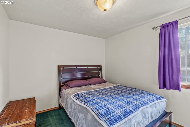 bedroom with a textured ceiling and dark carpet