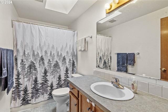 bathroom featuring decorative backsplash, a skylight, tile patterned floors, vanity, and toilet