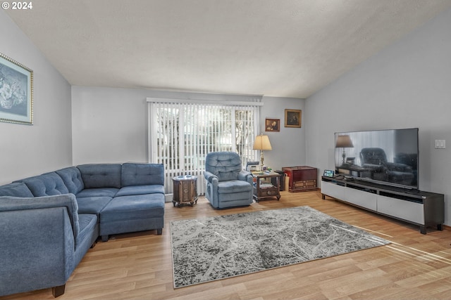 living room featuring a textured ceiling, vaulted ceiling, and light wood-type flooring